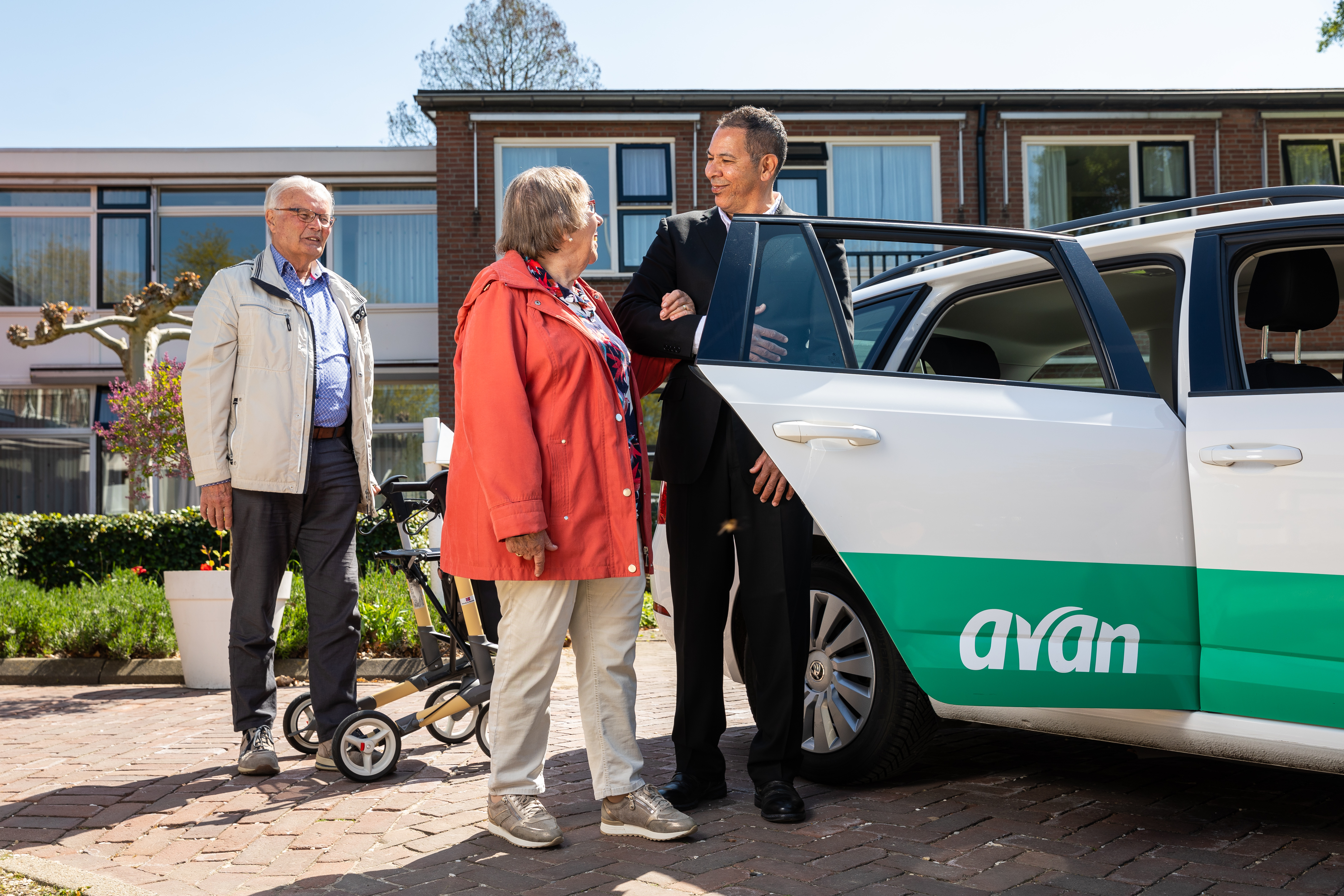 Een chauffeur helpt een vrouw met instappen in een Avan personenauto.